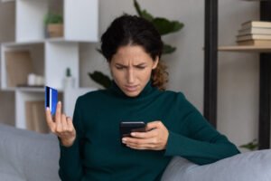 Mujer preocupada revisando cargos de su tarjeta revolving en el móvil